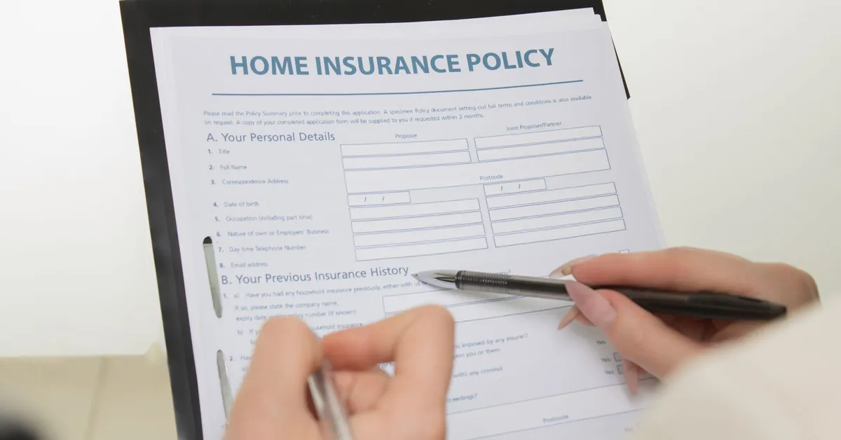 Hands holding pens filling out a home insurance policy document for coverage details. a home insurance policy