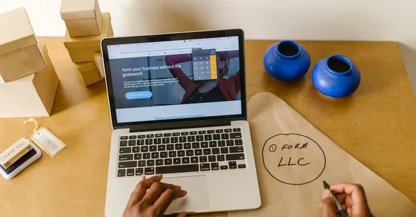 Workspace with laptop, packaging, and handwritten LLC notes, ideal for a small business startup scene. a person starting an online business