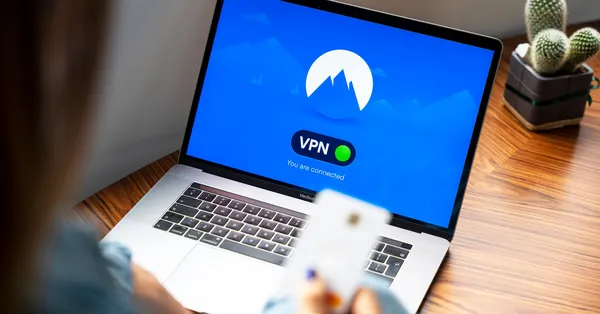 A person using a VPN on a laptop, symbolizing secure internet browsing in a modern indoor setting. macbook pro on brown wooden table
