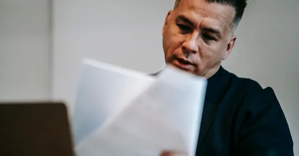 Professional man intently reviewing paperwork at his workstation indoors. photo of man reviewing the documents