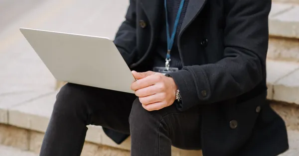 Crop anonymous male office employee in formal apparel with netbook working on project on street staircase crop manager with laptop on urban stairs