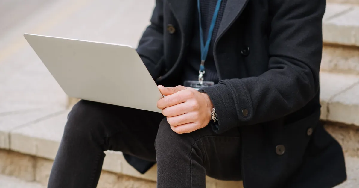 Crop anonymous male office employee in formal apparel with netbook working on project on street staircase crop manager with laptop on urban stairs