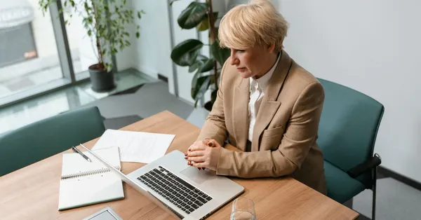 Professional woman in office setting working on a laptop, surrounded by office items. a woman sitting at a desk looking at her computer screen