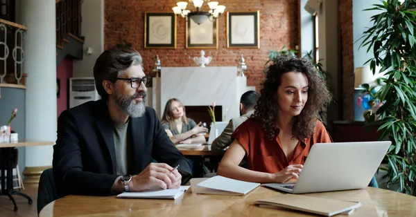 Business professionals collaborating over laptops and notes in a stylish workspace. a man and a woman working together
