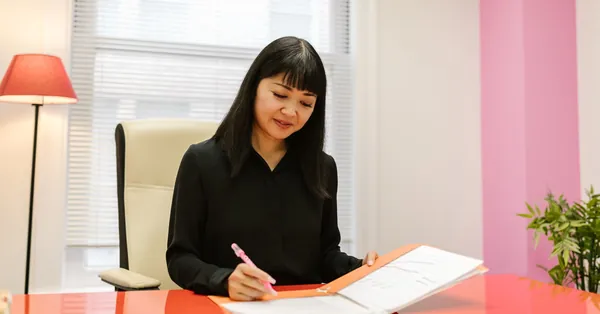 Asian woman working in a bright modern indoor office setting reviewing paperwork. a woman looking at a document