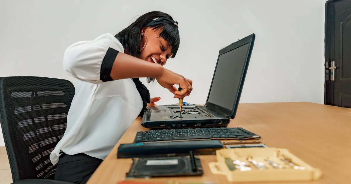 Woman repairing a laptop at a desk with tools, showcasing technology and skill. a woman repairing laptop