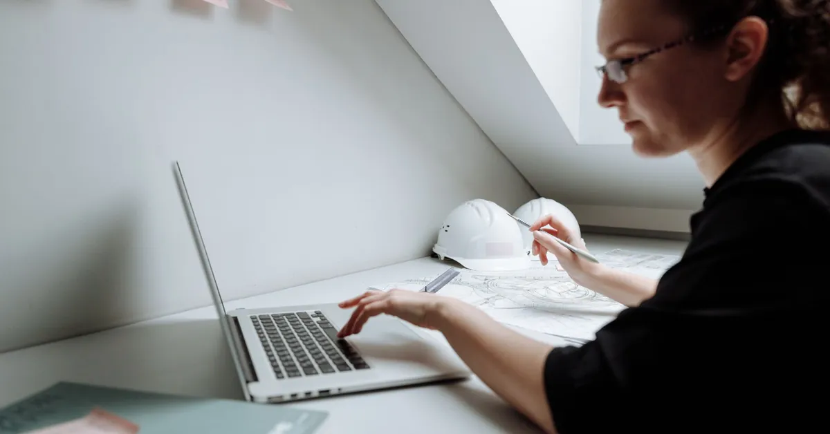 A focused architect working on building designs using a laptop in a modern office setting. close up photo of female architect using laptop