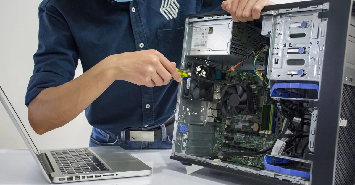 A technician repairs a desktop computer in an indoor setting, illustrating tech maintenance. a man wearing a face mask repairing a cpu